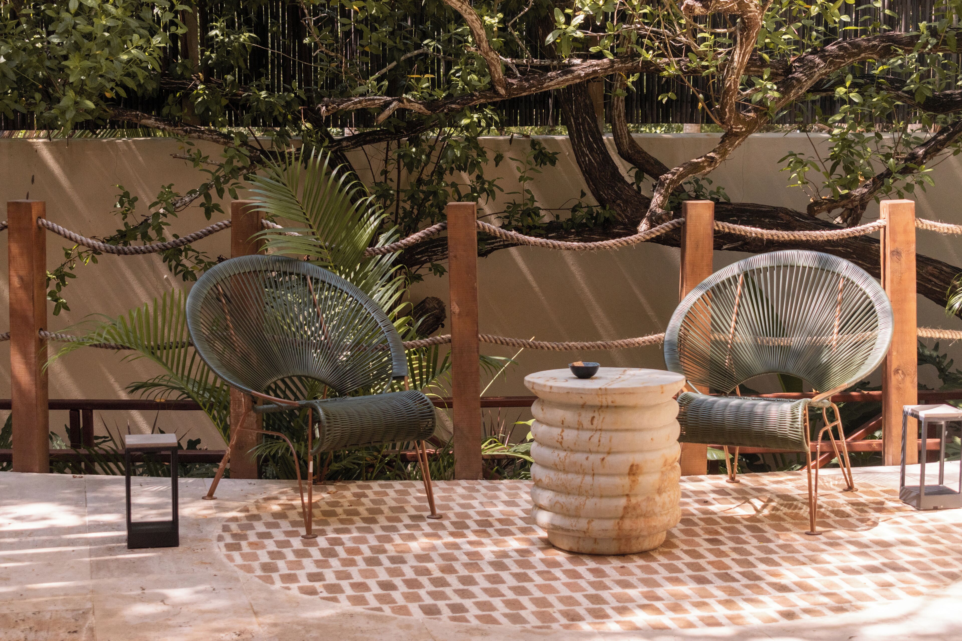 A patio area with two wicker chairs, a round table, and a small stool.