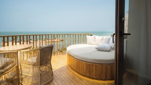 A round bed with white bedding on a wooden deck overlooking a beach. - Hotel Aimarawa (San Antero)