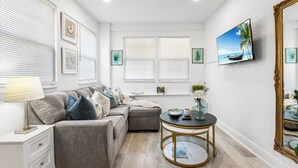 Ein modernes Wohnzimmer mit einer Couch, einem runden Couchtisch und einem an der Wand befestigten Fernseher.