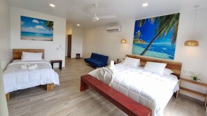 A hotel room with two beds, a bench, a blue sofa, and a large tropical mural. - Hilltop Treehouse amazing views near playa Avellanas Tamarindo (Pinilla)