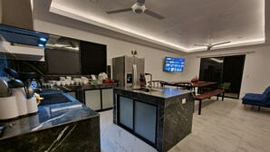 A modern kitchen with a central island, built-in appliances, and a flat-screen TV mounted on the wall. - Hilltop Treehouse amazing views near playa Avellanas Tamarindo (Pinilla)