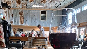 Un interior rústico con una barra de madera, una copa de vino tinto y botes de especias sobre la encimera.