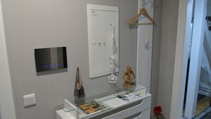Een moderne badkamer met een glazen plank, een spiegel, een wandlamp en een deur met een handgreep.