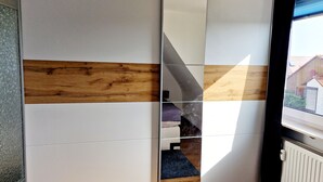 Een kamer met een schuifdeurkast met een combinatie van witte en houten panelen.