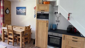 Une cuisine compacte avec des meubles en bois, un four encastré et une machine à café.
