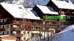 Un bâtiment de style chalet, doté de nombreux balcons et d’un toit enneigé, ce qui suggère un décor hivernal.