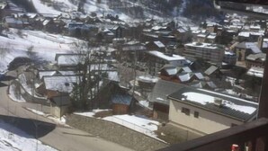 Un village de montagne enneigé, avec des maisons traditionnelles et une vue dégagée sur les montagnes.