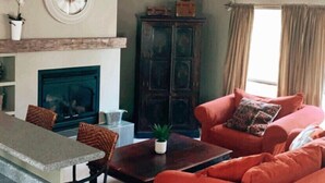 A living room with a fireplace, a dining area with a table and chairs, and a sofa. - Hideaway in The Blue Mountains ***all seasons*** (The Blue Mountains)