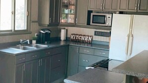 A kitchen with grey cabinets, a stainless steel sink, a microwave, and a refrigerator. - Hideaway in The Blue Mountains ***all seasons*** (The Blue Mountains)