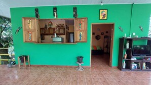 A room with a green wall, wooden cabinets, a television, and a small table. - Peyo 's House (Puerto Viejo de Talamanca)