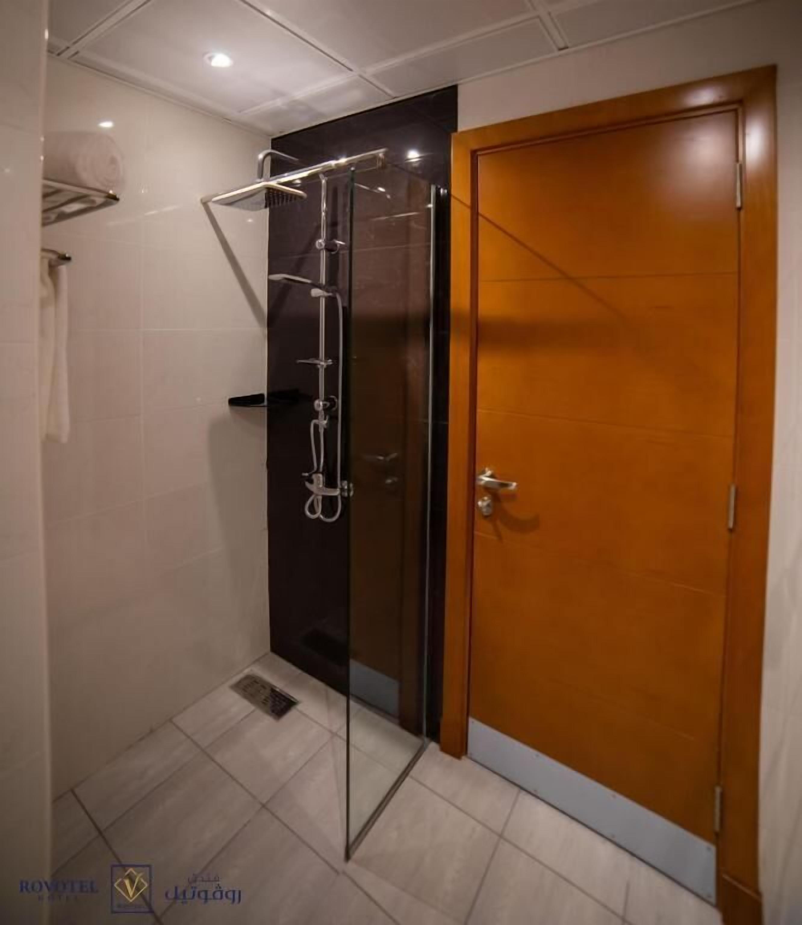 A bathroom with a shower, a wooden door, and tiled walls.