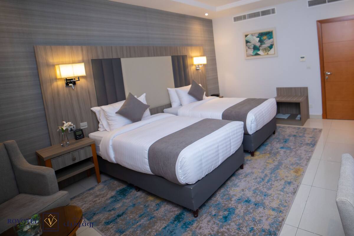 Une chambre d’hôtel avec deux lits, une télévision, un bureau et une salle de bain.