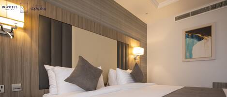 A hotel room with a large bed, two bedside lamps, a nightstand, and a painting on the wall.