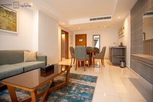 A modern hotel room with a living area, dining space, and a kitchenette.