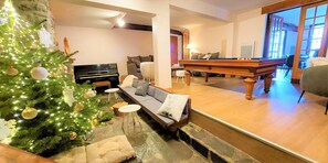 Un salon chaleureux avec un piano, un canapé, un sapin de Noël et une table de billard.