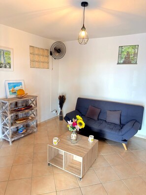 A living room with a sofa, coffee table, and a fan.