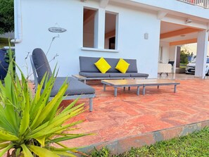 A modern outdoor seating area with a sofa and a table, a sign indicating a bar, and a vehicle in the background. - Chez Kelly et Nicolas, le Paradis de Sofaia (Sainte-Rose)