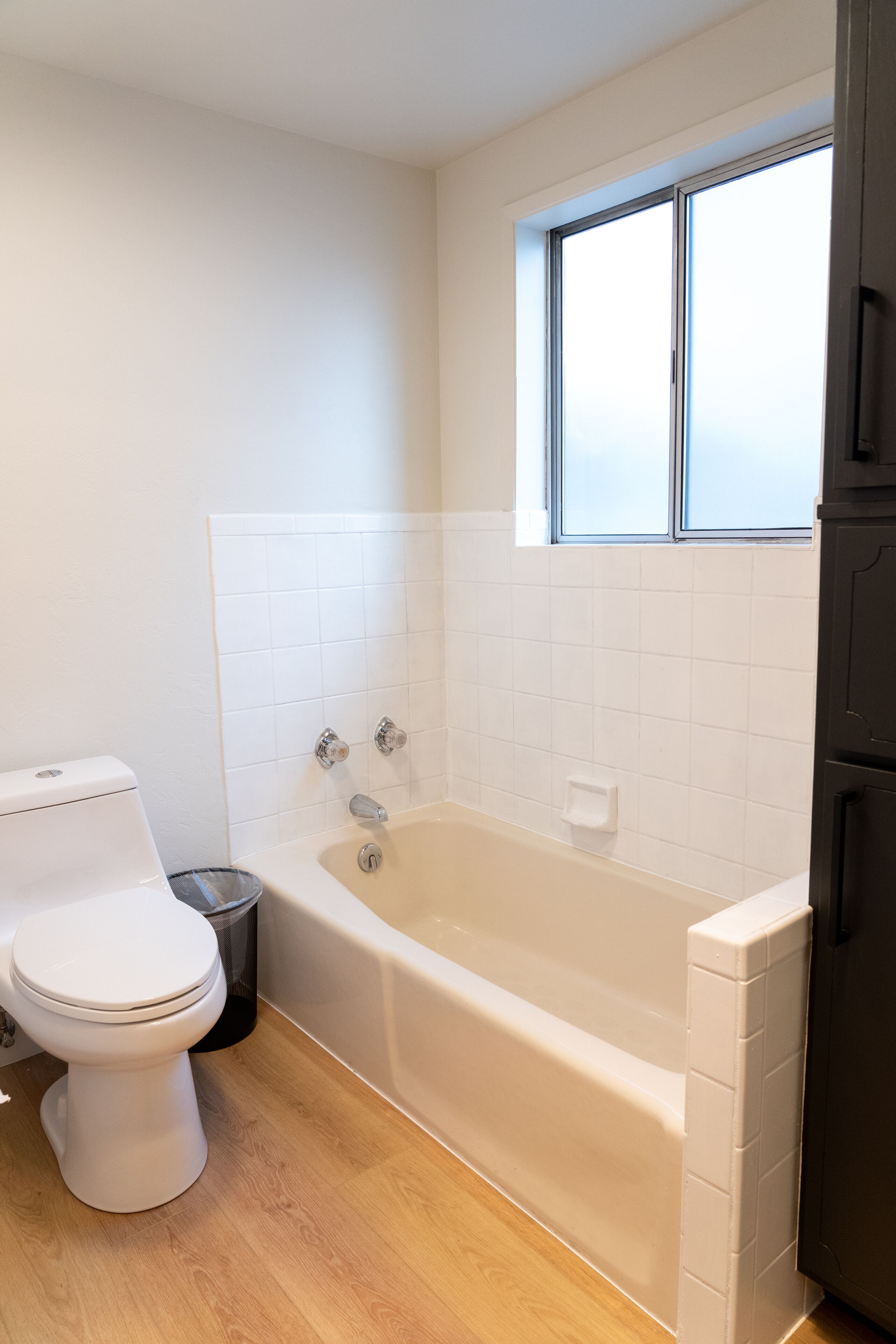 Un bagno con il water bianco, una vasca e una finestra.