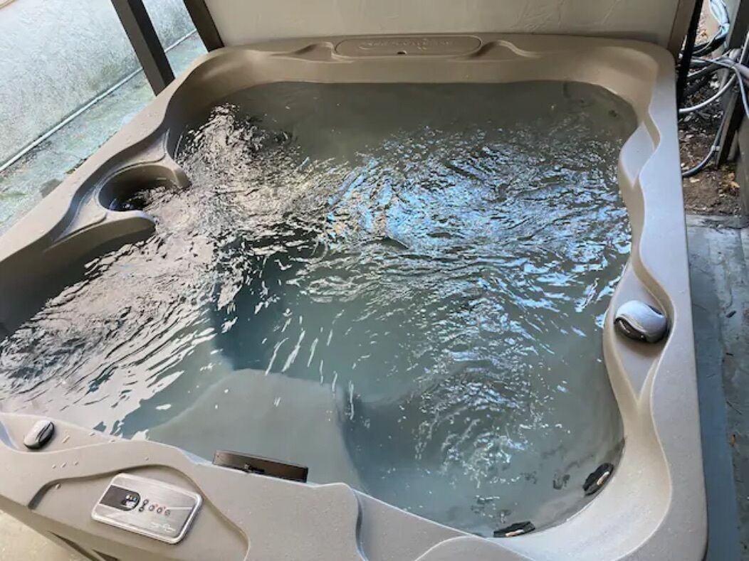 Een jacuzzi met water, een bedieningspaneel en een afvoer.