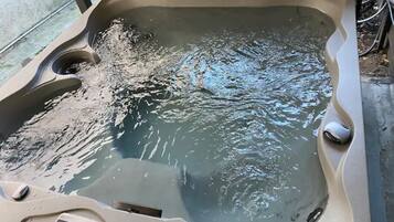 Een jacuzzi met water, een bedieningspaneel en een afvoer.