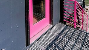 A building with a bright pink door and a black exterior. - Large Home + Sleeps 20 + Hot Tub + Backyard Oasis + Optional add-on CABOOSE (Denver)