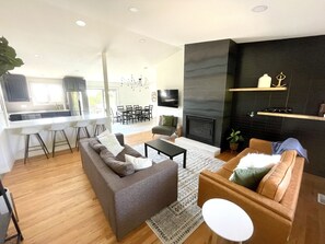 Una sala de estar moderna con un sofá, una mesa de centro y una chimenea. Hay una zona de cocina con una mesa de comedor y sillas.