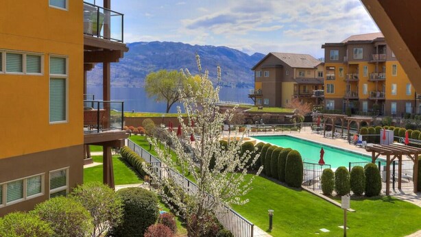 Ein Hotel mit Pool, grünen Rasenflächen und Bergblick.