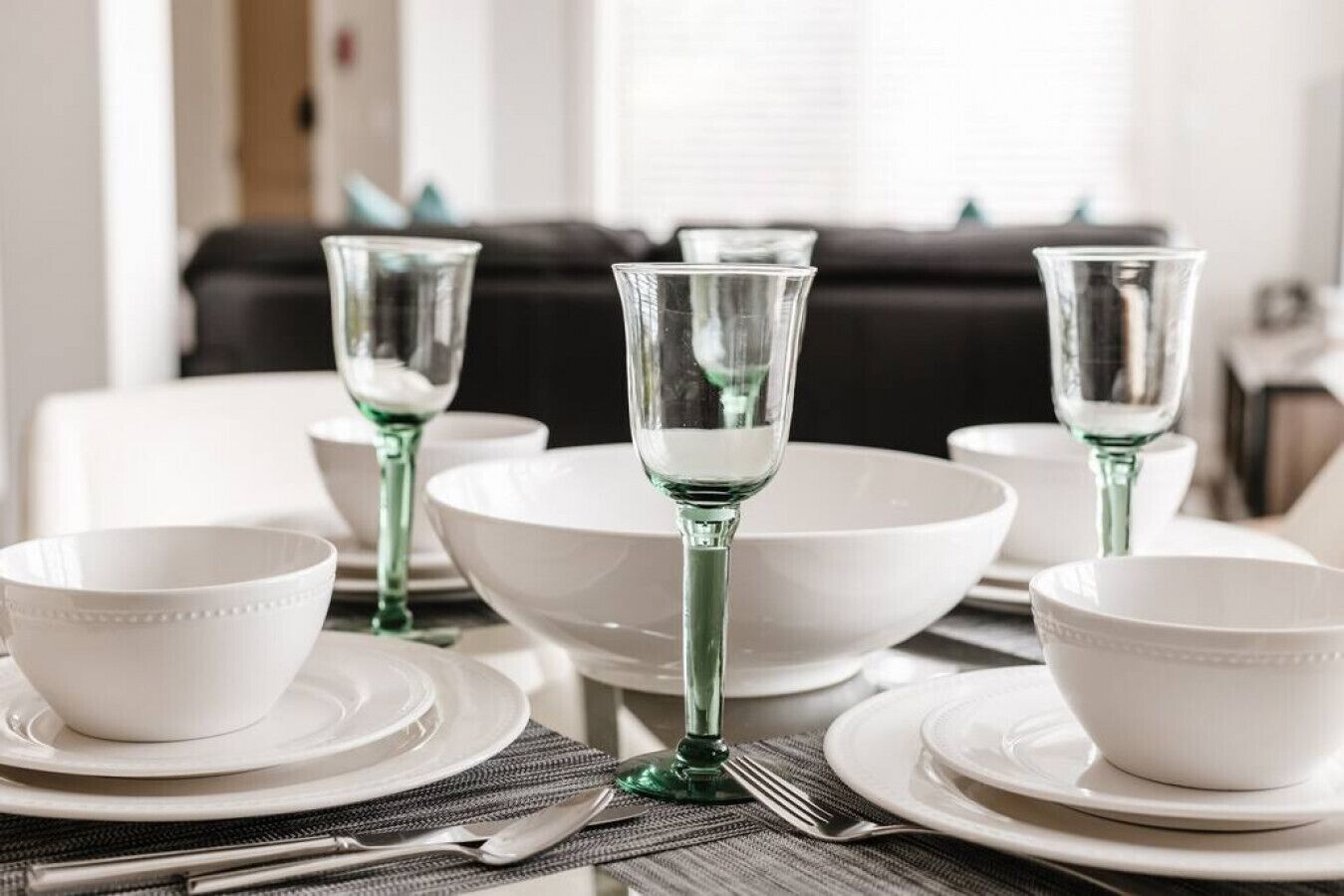 Mesa para comer con cuencos blancos, platos y vasos verdes.
