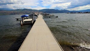 Un muelle de madera que se adentra en un lago, con barcos amarrados al final.