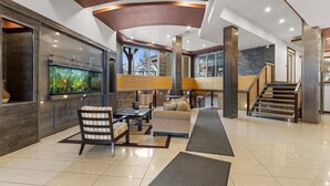 Un salón espacioso con un gran acuario, asientos cómodos y una escalera que sube a otro nivel.