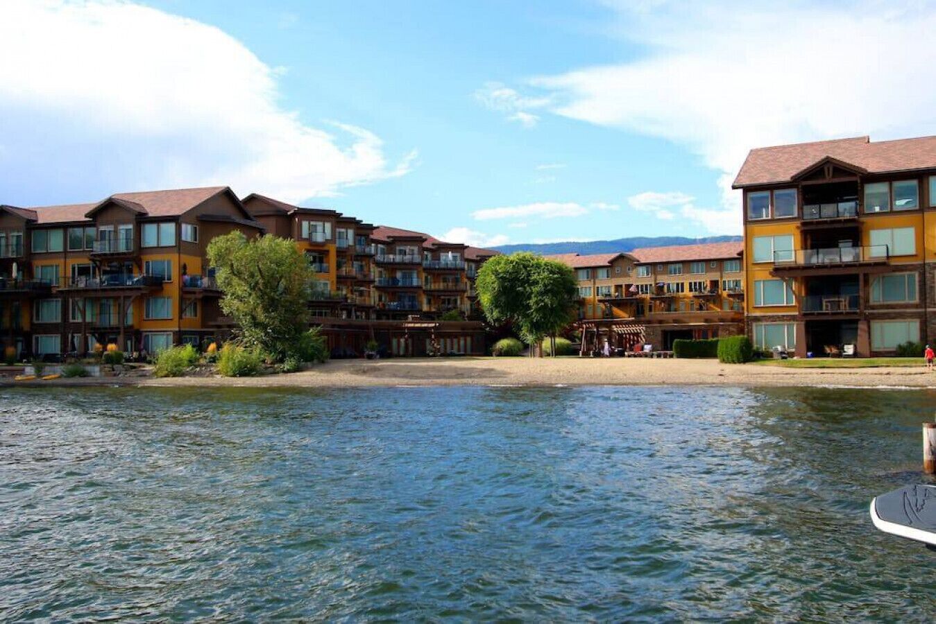 A waterfront hotel with multiple balconies, a central courtyard, and a view of the water.