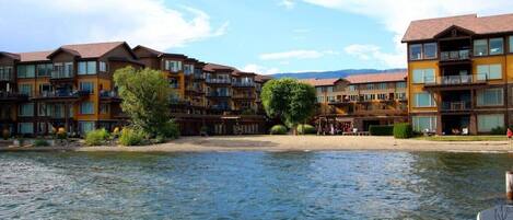 A waterfront hotel with multiple balconies, a central courtyard, and a view of the water.
