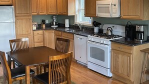 Une cuisine avec des meubles de rangement en bois, une cuisinière à gaz, un four à micro-ondes et une machine à café.