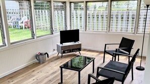 A sunlit room with a TV, a glass table, and black chairs. - Stay just a short walk -0.3- miles from Lambeau! (Green Bay)