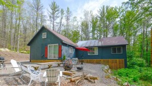 Une cabane dotée d’un patio en gravier, de meubles d’extérieur et surplombant une forêt.