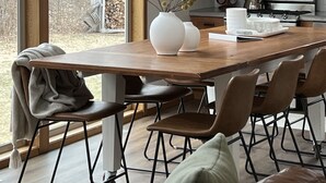 Eine moderne Küche mit einem großen Fenster, Holzschränken, einer Edelstahl-Mikrowelle und einem Essbereich mit einem Holztisch und Stühlen.