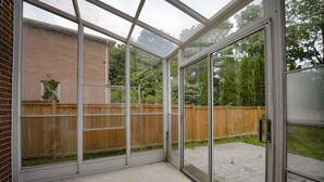 Ein Wintergarten mit Blick auf ein Backsteingebäude und einen Holzzaun.