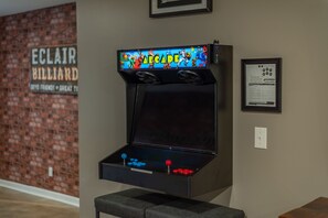 A retro arcade machine with a colorful screen and joystick, placed against a brick wall with a sign reading "ECLAIR BILLIARD".