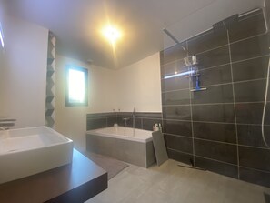 Een bad/douchecombinatie, een haardroger, handdoeken, zeep
