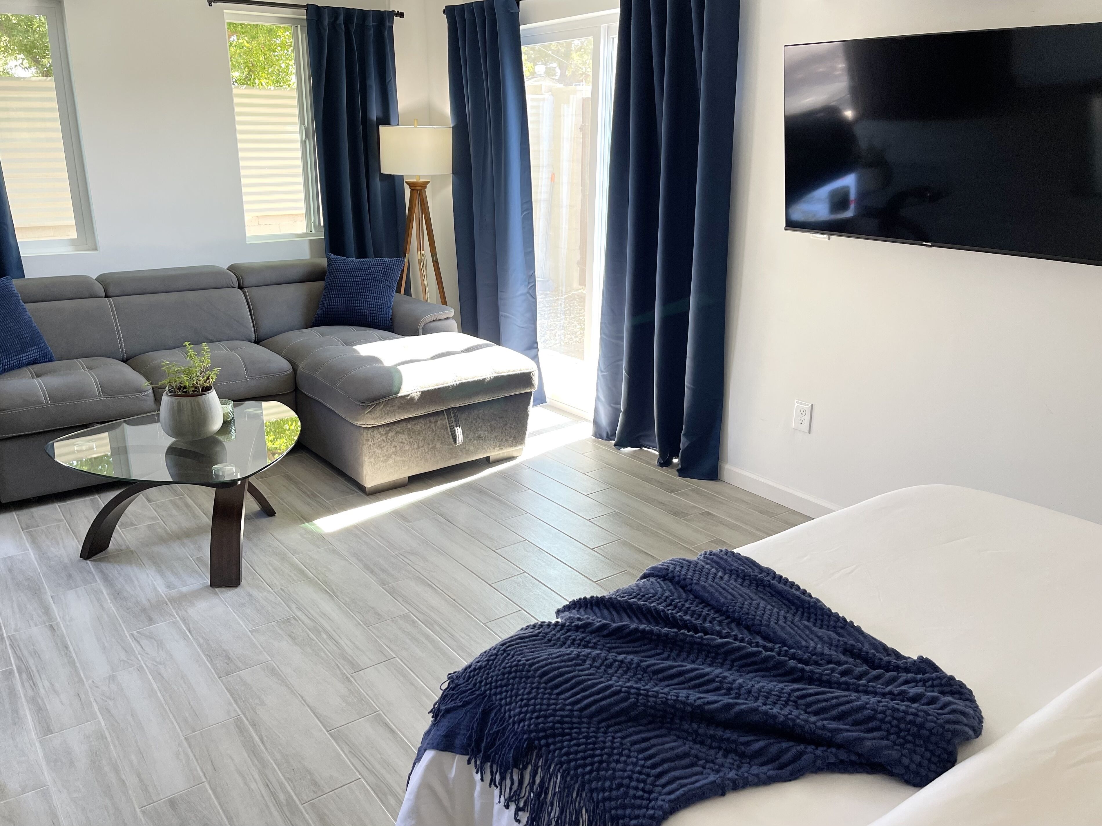A modern living room with a sofa, ottoman, and a TV mounted on the wall.