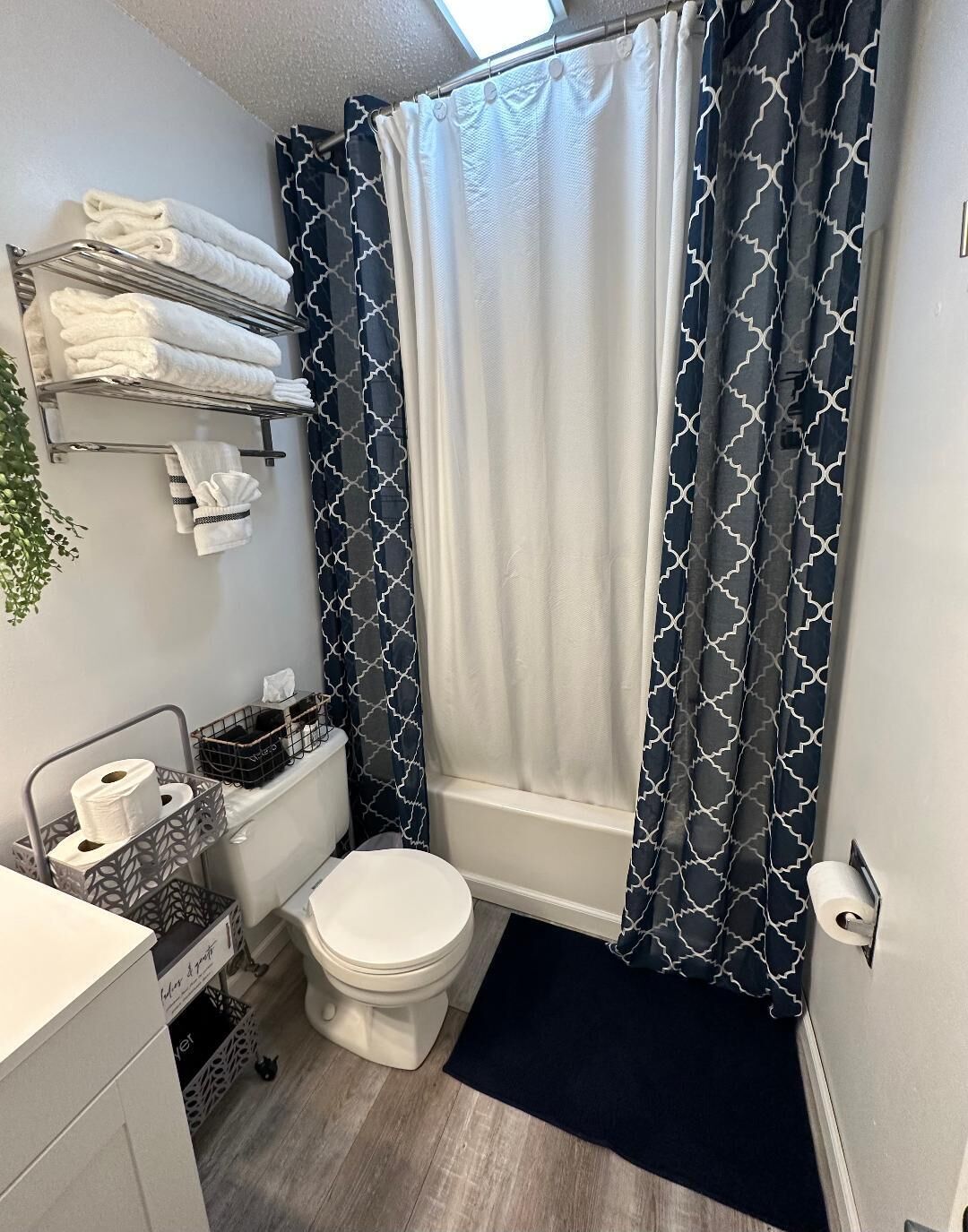 A compact bathroom with a toilet, a shower curtain, and a towel rack.