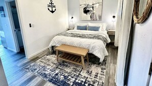 A bedroom with a bed, a bench, a ceiling fan, and a rug.
