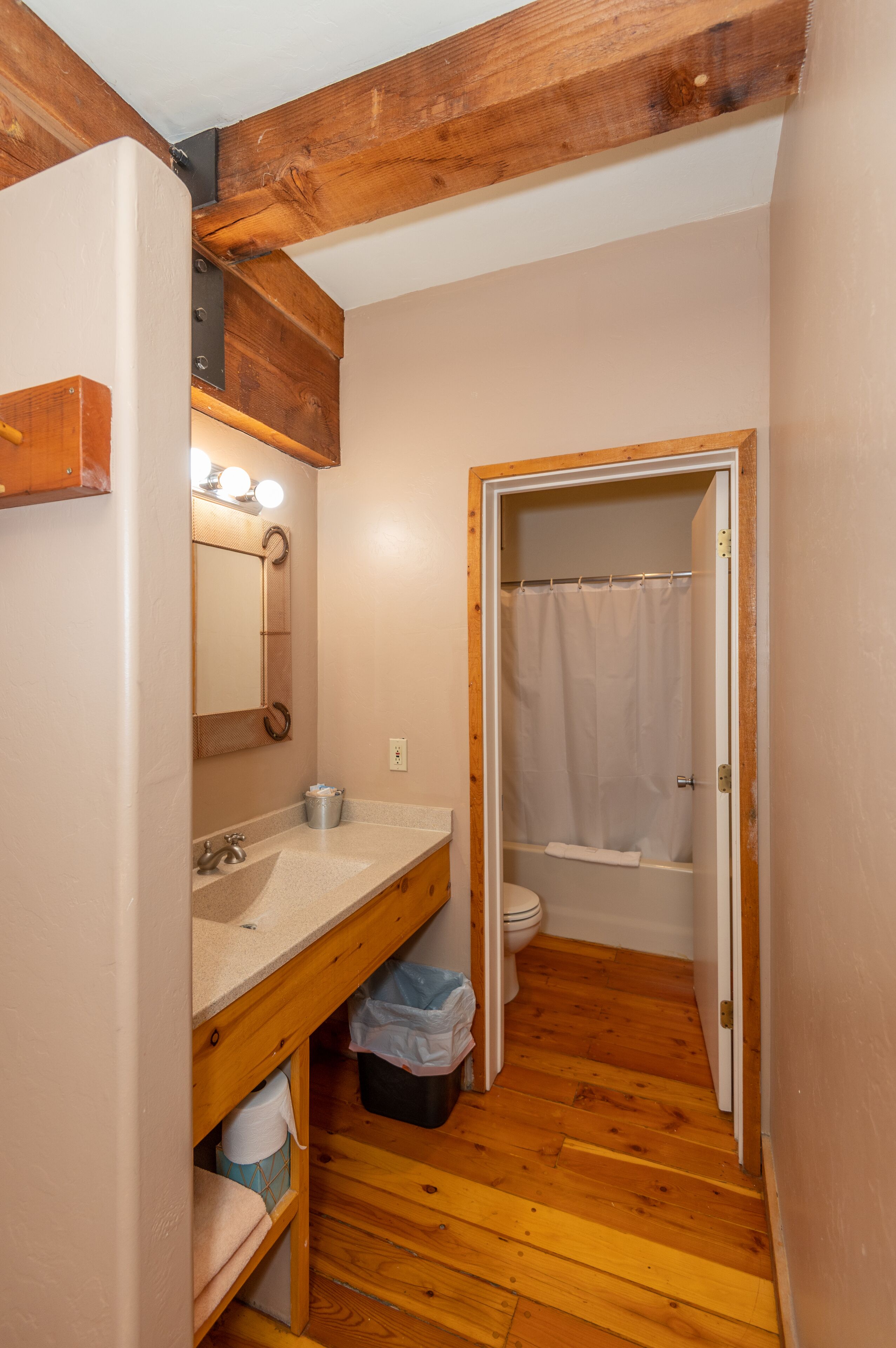 Une salle de bain avec un meuble-lavabo en bois, un miroir, un lavabo et un espace douche.