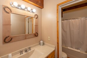 Un baño con un espejo grande, tocador y cortina de ducha.