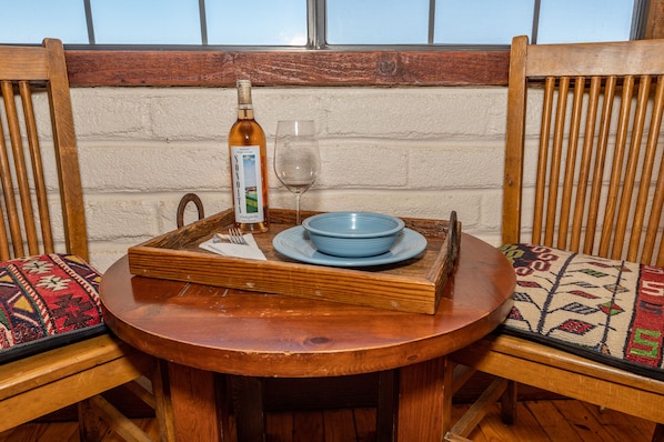 Una mesa de madera con una bandeja, una botella, un vaso y un tazón.