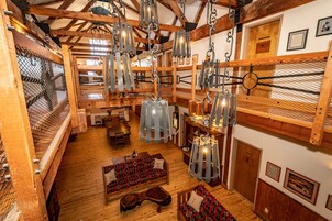 Interior rústico com vigas de madeira, luminárias pendentes e um espaço de estar acolhedor.