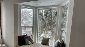 Una habitación con un banco incorporado junto a un amplio ventanal con vistas a un paisaje nevado.