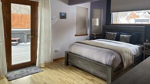 Un dormitorio con cama, ventilador de techo, ventana con persianas y puerta que da a un balcón.