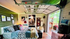 A compact, well-lit room with a bed, a small seating area, and a kitchenette.