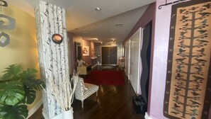 A hallway with a wooden floor, a patterned wall, a red carpet, and a door with a tree design.